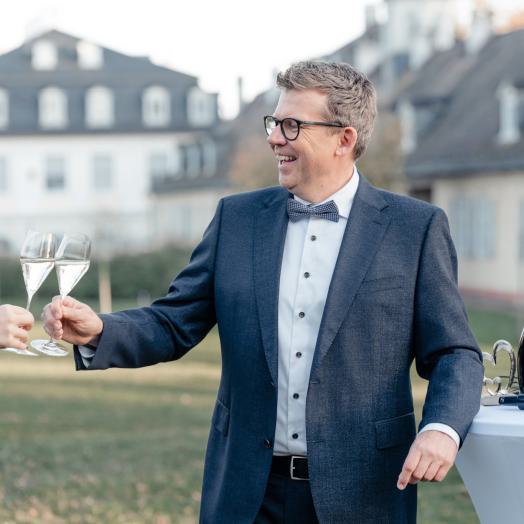 Andreas Luck stößt mit einem Sektglas in der Hand an