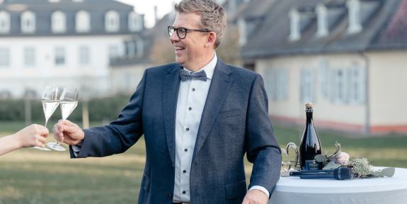 Andreas Luck stößt mit einem Sektglas in der Hand an