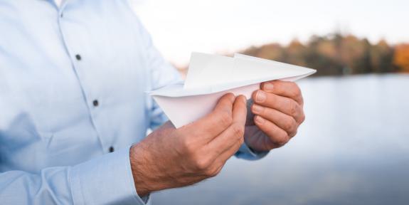 Andreas Luck hält einen Papierflieger in den Händen