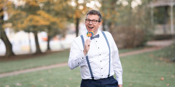Andreas Luck hält einen Regenbogen Lolli in der Hand