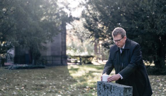 Andreas Luck zündet auf einem Friedhof eine Kerze an