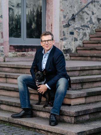 Andreas Luck sitzt mit seinem Hund auf einer Steintreppe